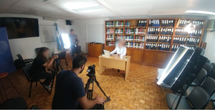Equipo de video grabando un testimonio en un cuarto con una biblioteca grande